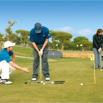 Ein Mann und eine Frau üben auf einem Golfplatz die richtige Schlägerhaltung beim Golfen und erhalten Anweisungen von einem Golflehrer