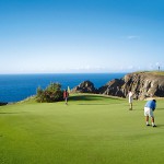 Vier Golfer spielen auf dem Golfplatz von Porto Santo direkt an der Küste mit Ausblick auf das Meer