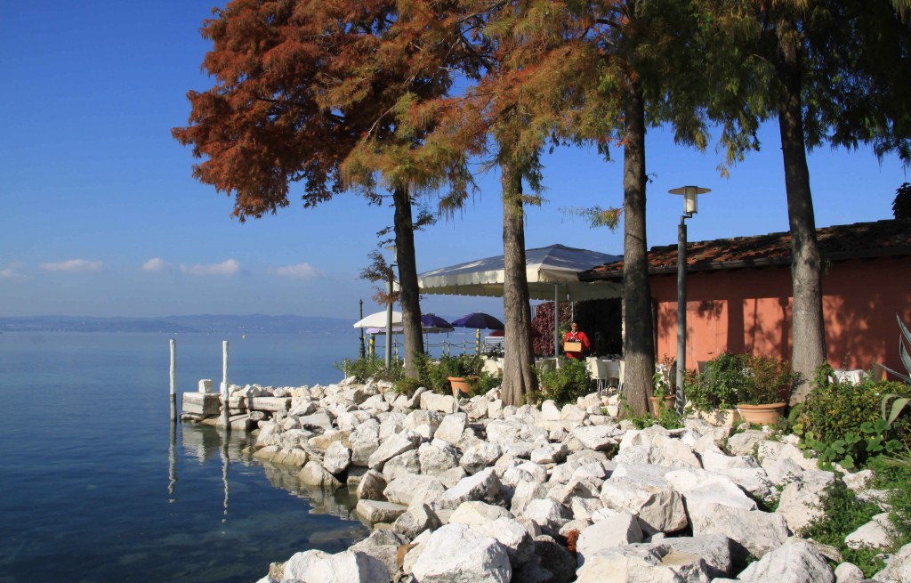 Gardasee im Hintergrund mit einer Terrasse eines Restaurants