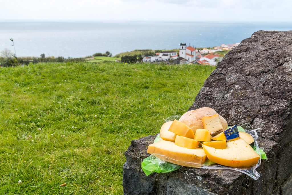 Käse auf einem Felsen und im Hintergrund ein Dorf und das Meer