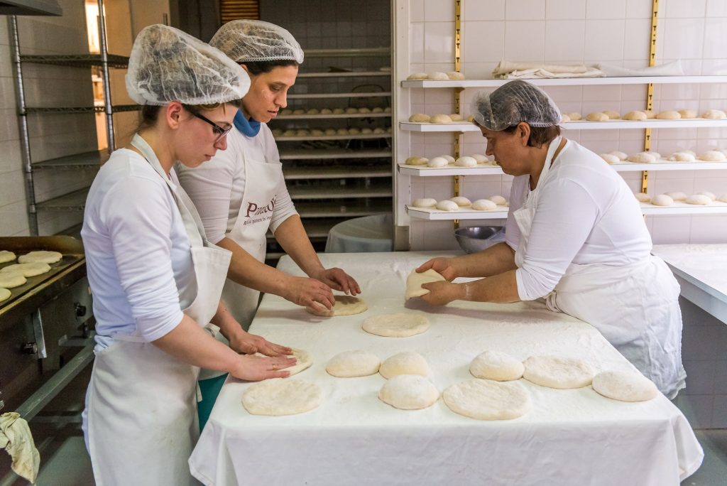 Die Kügelchen aus Teig werden platt gedrückt; von Hand 