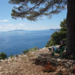 Mann auf Bank blickt auf kroatische Küste und vorgelagerte Inseln