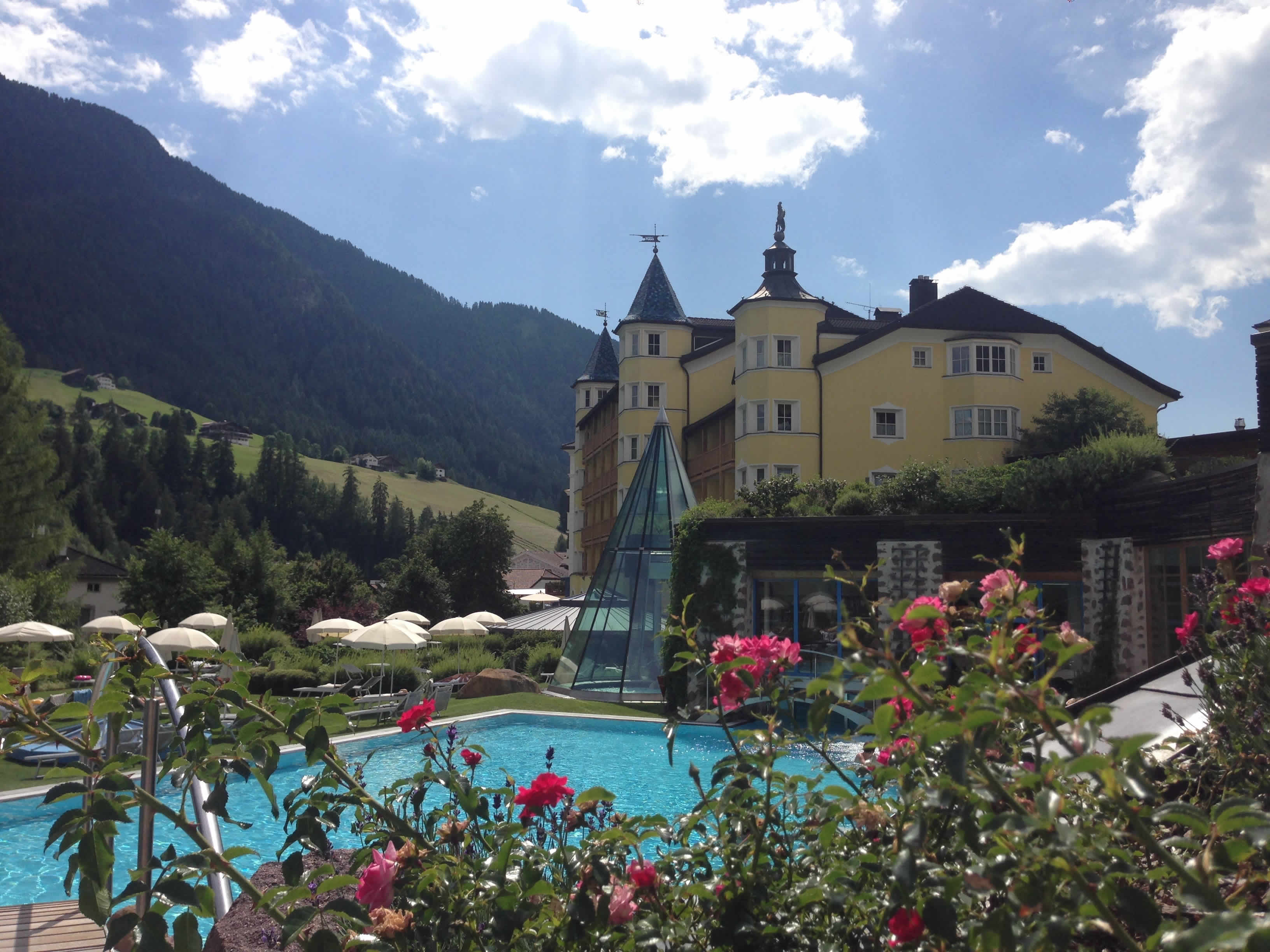 Blick auf Pool, Garten und Fassade Adler Dolomiti Spa Hotel