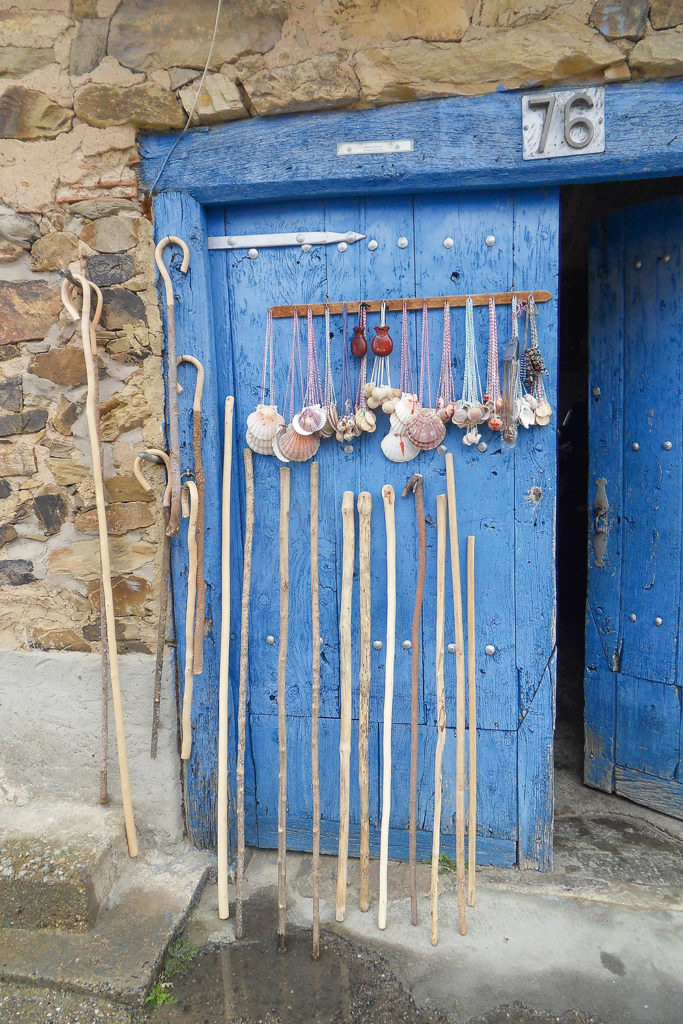 Blaue Tür mit Wanderstöcken und einer Muschelgirlande 