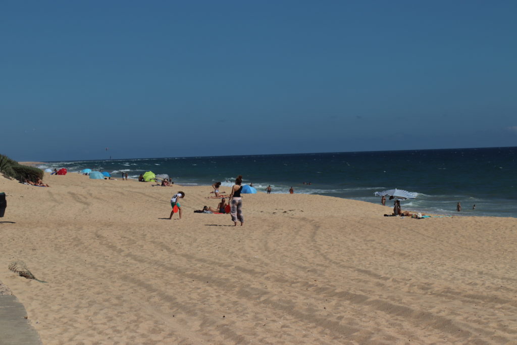 Strand mit ein paar Menschen, die auf Abstand dort liegen 