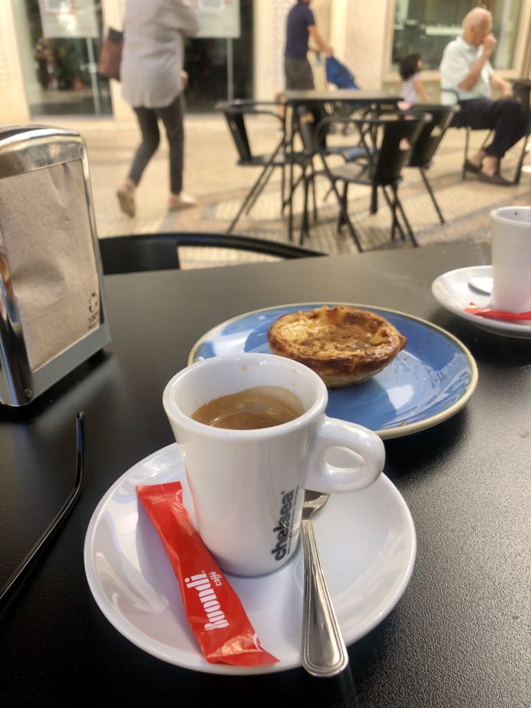 Pastel de Nata und ein Kaffee auf einem Tisch in der Außengastronomie 