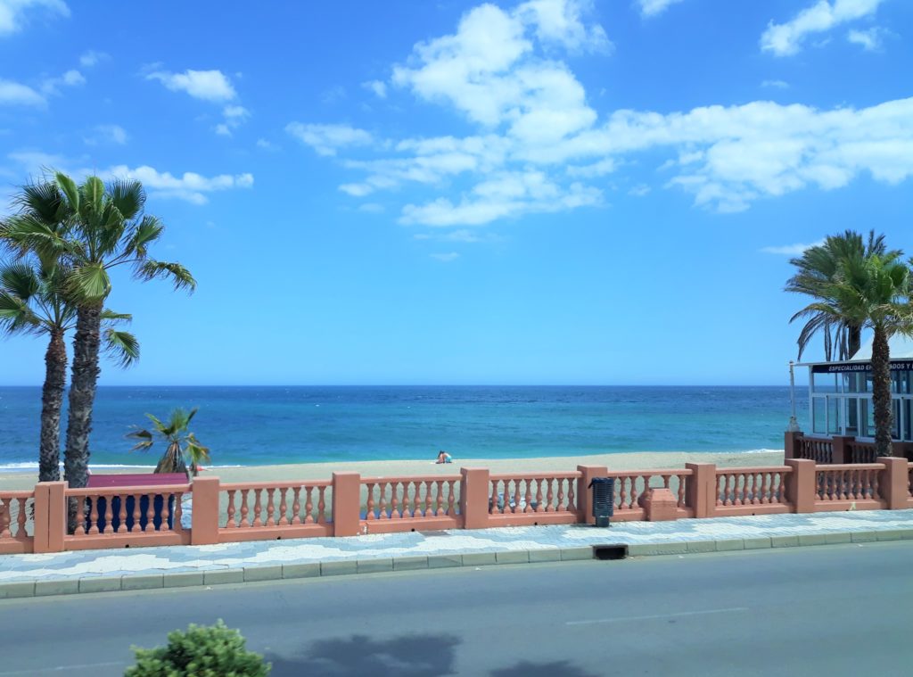 Straße mit Blick auf einen fast menschenleeren Strand 