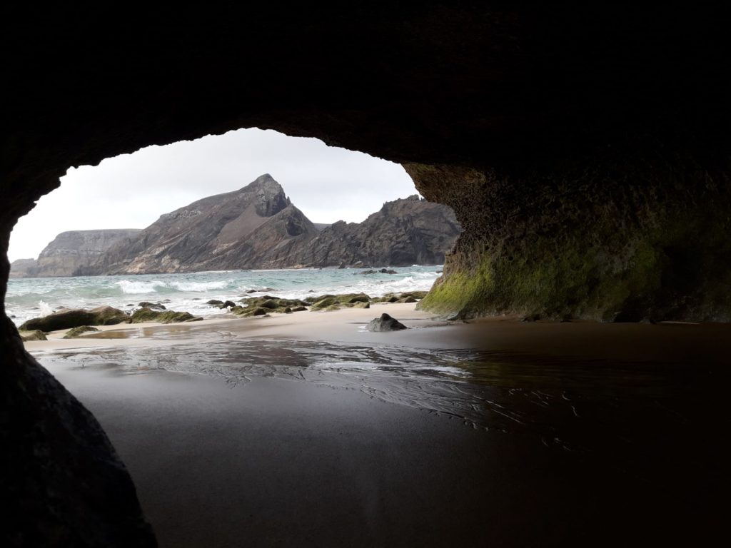 Blick auf das Meer und auf einen felsigen Hintergrund, von einer „Höhle“ aus 