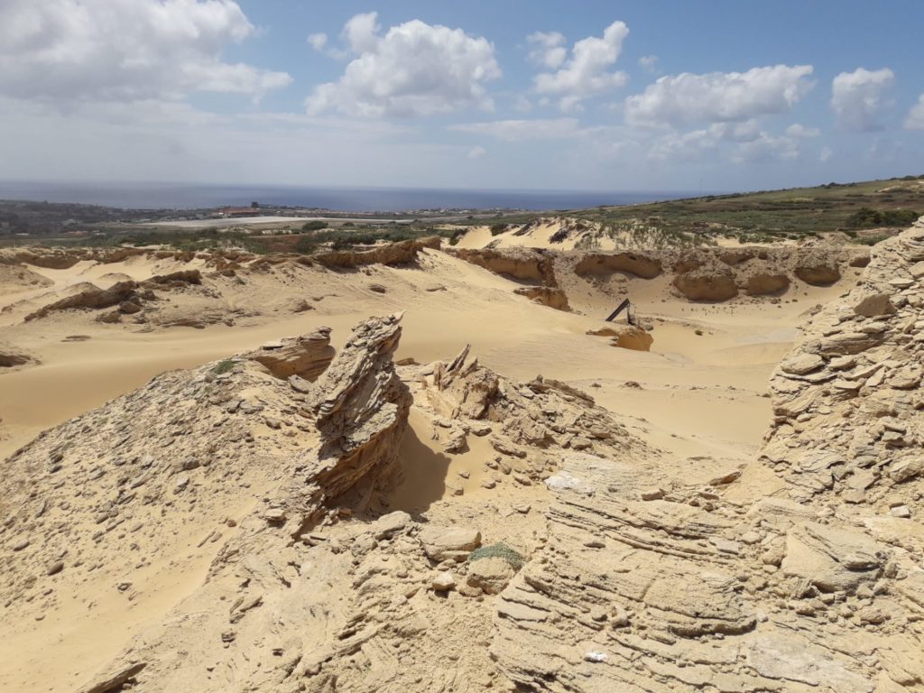 Blick auf Felsen, Sand und in der Ferne das Meer 