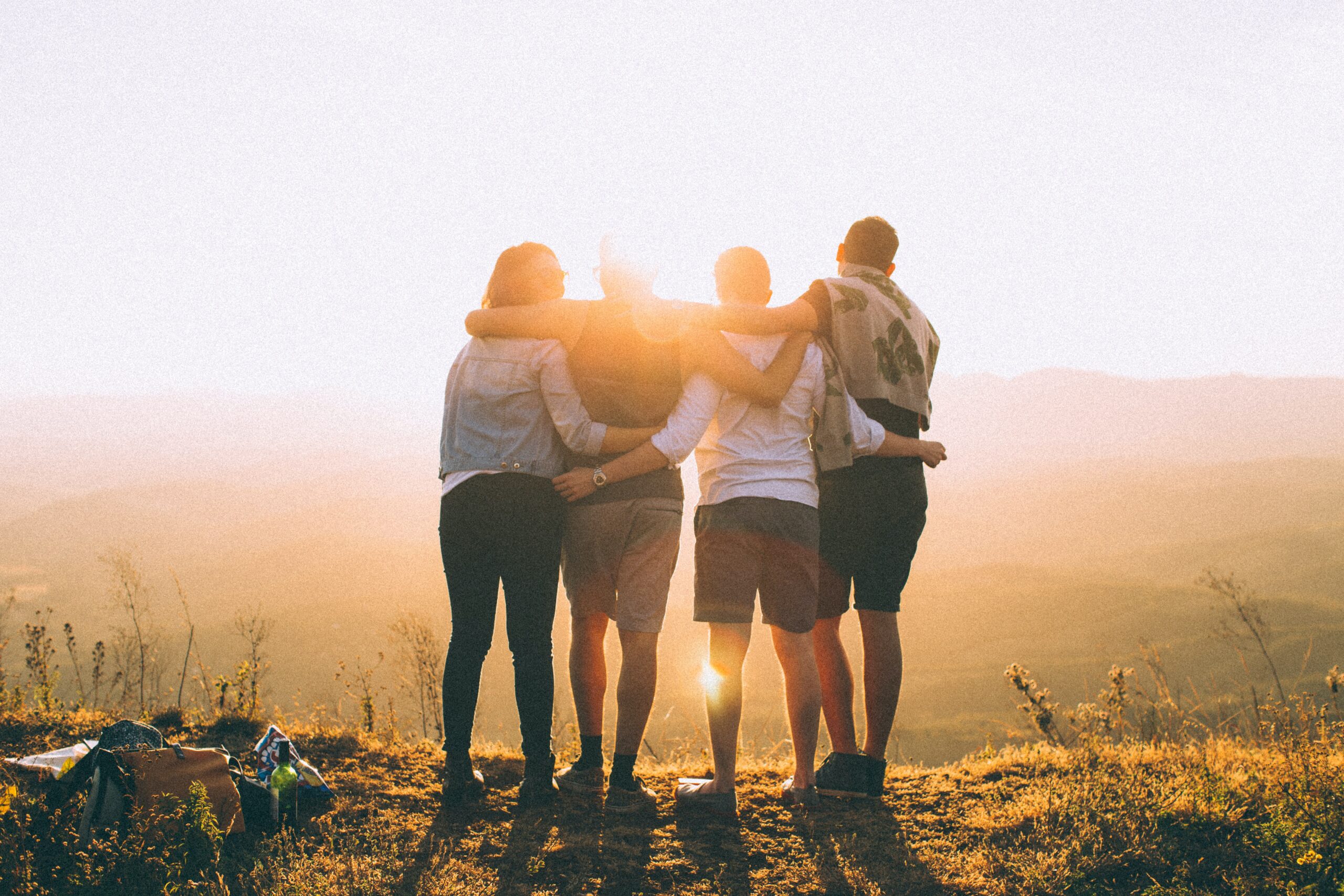 Vier Menschen die sich in den Armen halten und auf den Sonnenuntergang gucken