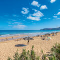 Sandstrand mit blauem Meer auf Madeira. Im Hintergrund Berge