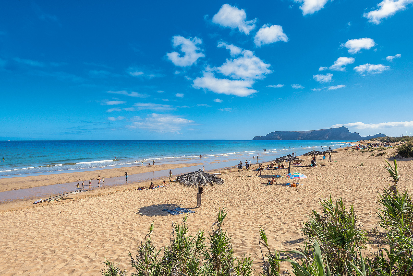 Sandstrand mit blauem Meer auf Madeira. Im Hintergrund Berge