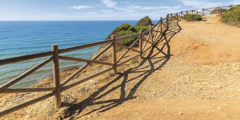 Holzgeländer an der Küste an der Algarve mit Blick auf das Meer