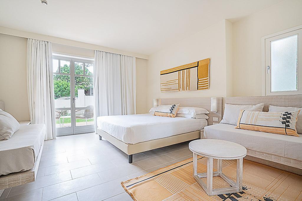 Hotel La Coluccia, Heller Wohn- und Schlafbereich in einer Garden Junior Suite.