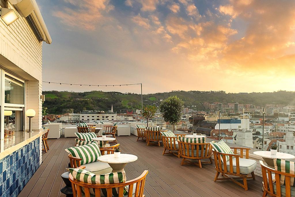 Hotel Ercilla de Bilbao Autograph Collection, Sonnige Dachterrasse mit komfortablen Loungemöbeln, Sonnenschirmen und einem weiten Ausblick.