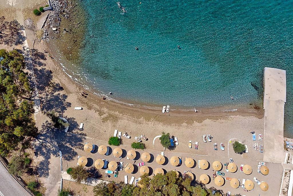 Evia Riviera Resort, Blick auf die hoteleigenen Sonnenstühle und Sonnenschirme am feinsandigen Strand.