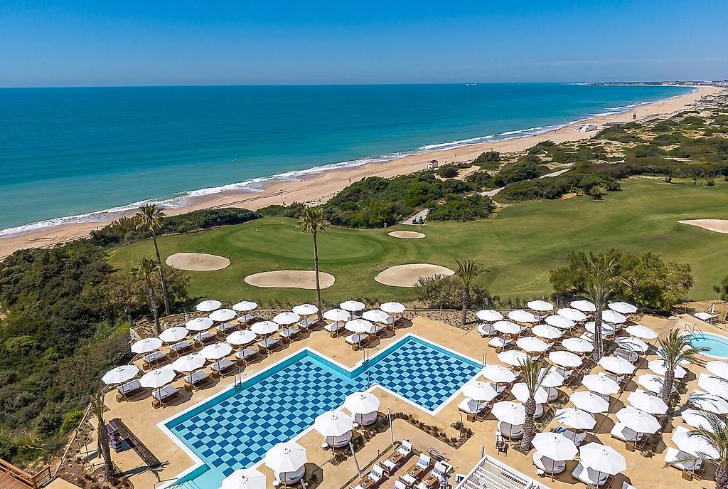 Amàre Beach Hotel Sancti Petri, Sonnenterrasse am Pool mit modernen Liegen und Sonnenschirmen.