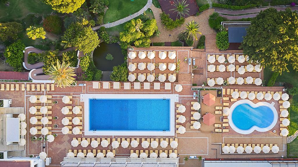 Hotel Don Carlos Marbella, Die Poollandschaft des Hotels bei strahlendem Sonnenschein und blauem Wasser.