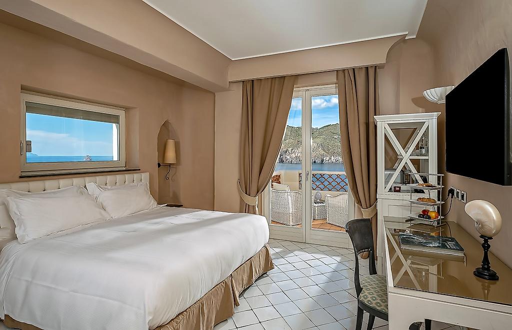 Therasia Resort Sea & Spa, Modernes Comfort-Zimmer mit Doppelbett und hellem Dekor sowie Blick auf das Meer.