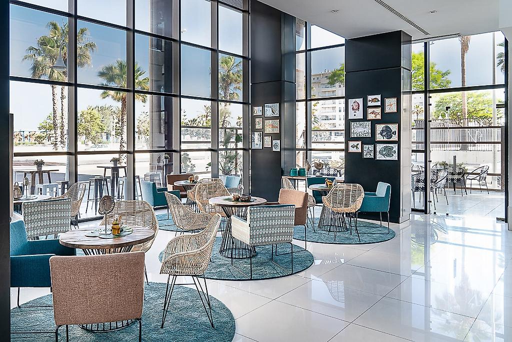Hotel Catalonia Málaga, Helle, großzügige Hotellobby mit modernen Sitzgelegenheiten und dekorativen Elementen.