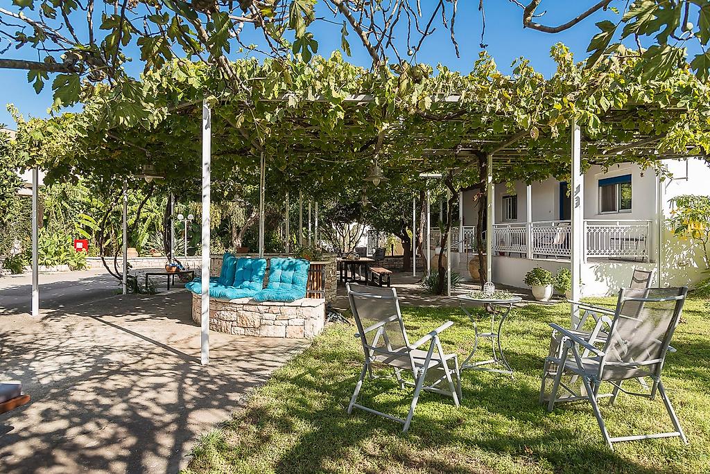 Villa Ganios, Sonnige Terrasse im Garten mit komfortablen Sitzmöbeln umgeben von üppigem Grün.