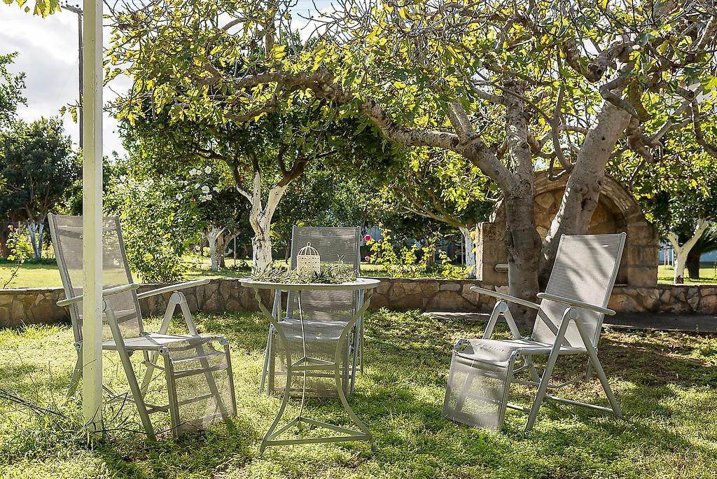 Villa Ganios, Blick durch blühende Sträucher auf die weitläufige, grüne Gartenanlage des Hotels.