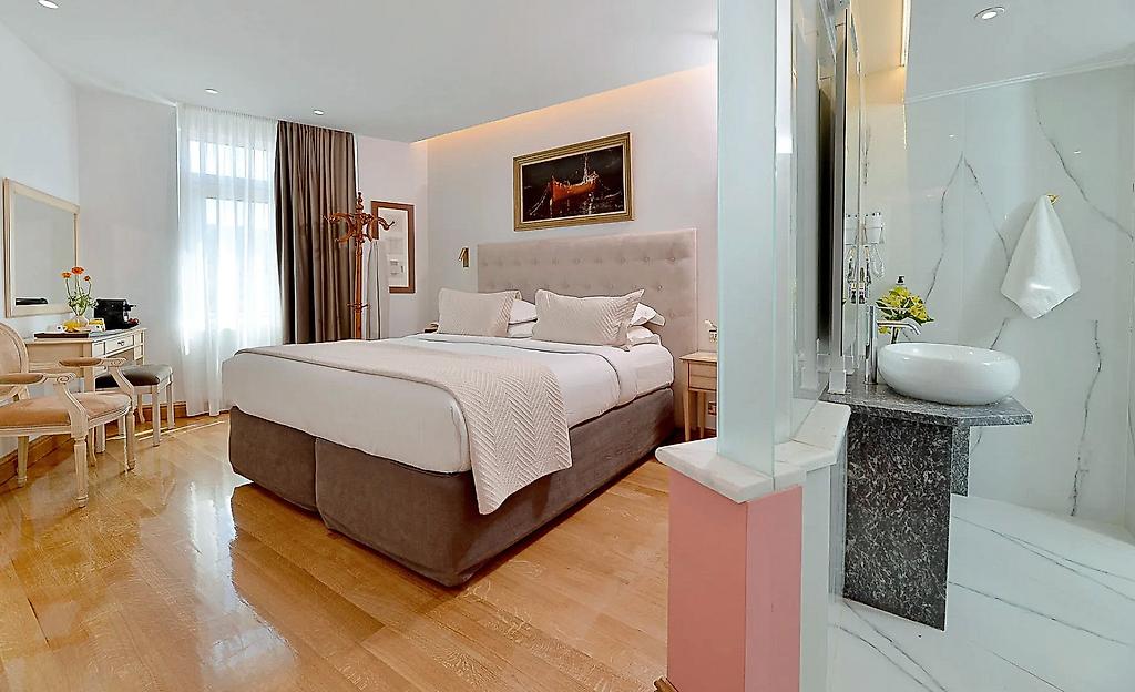 Acropolian Spirit Boutique Hotel, Gemütlicher Schlafbereich eines Zimmers mit dezenter Beleuchtung und harmonischer Farbgestaltung.