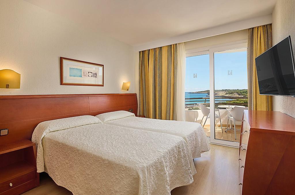 Hipotels Dunas Cala Millor, Komfortables Zimmer mit Doppelbett und warmen Tönen.