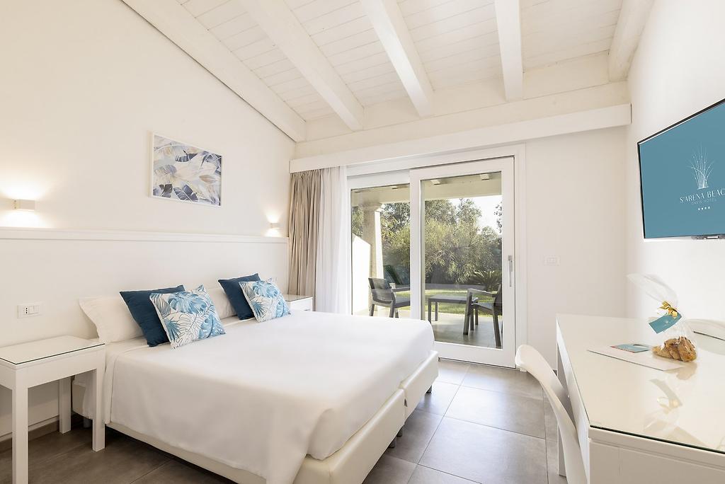 Hotel S’Arena Beach, Klassisches Hotelzimmer mit hellem Holzmobiliar und dekorativen Kissen
