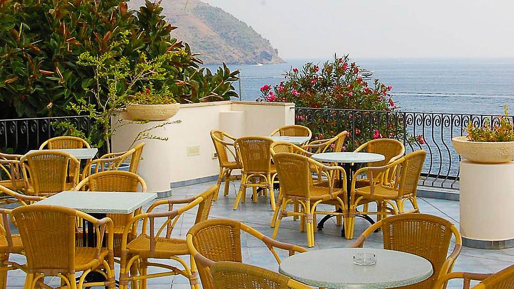Hotel Giardino sul Mare, Sonnenverwöhnte Hotelterrasse mit Tischen und Stühlen für entspannte Stunden im Freien.
