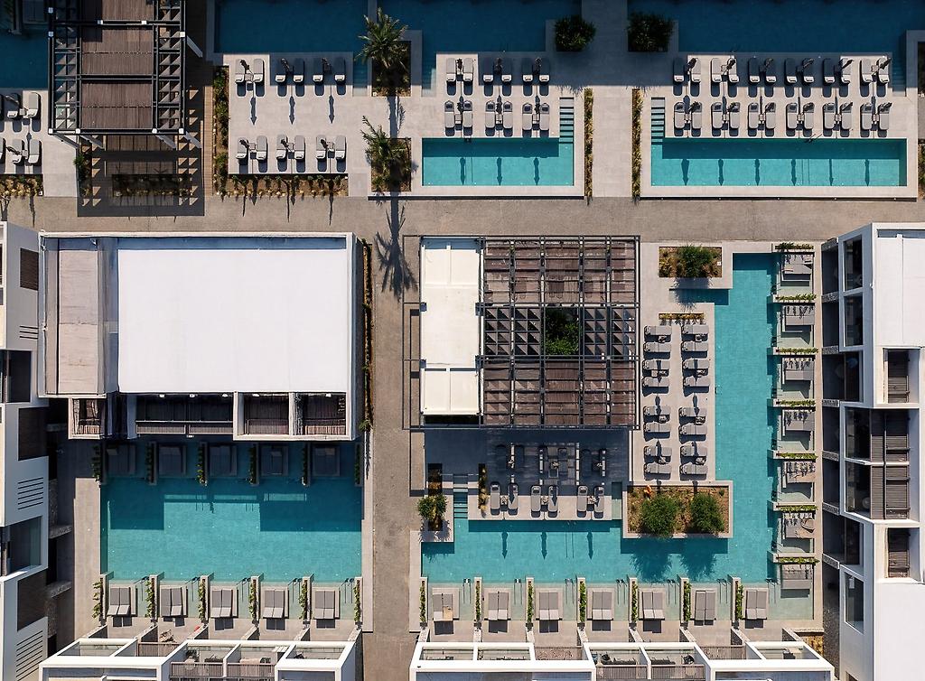Mosay All Suite Hotel, Außenansicht des modernen Hotelgebäudes bei Tageslicht mit umliegenden Palmen.