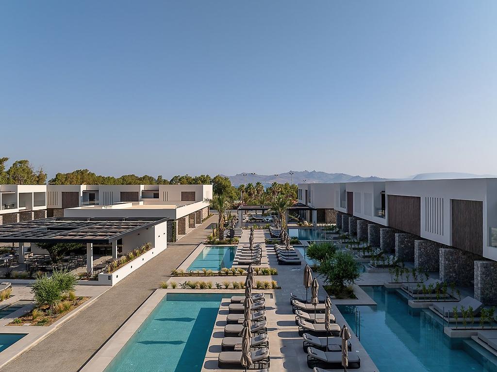 Mosay All Suite Hotel, Perspektive auf die Fassade des Hotelgebäudes mit Balkonen und gepflegten Außenanlagen.