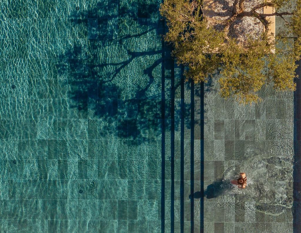 The Ritual, Poolbereich von der Seite fotografiert mit Palmen und Blick auf die Hotelanlage.