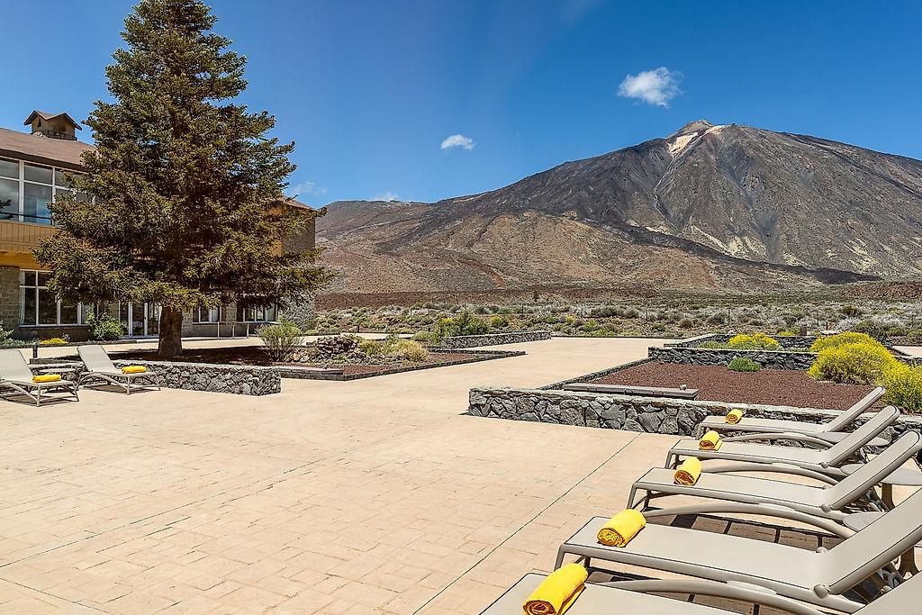 Parador Cañadas del Teide, Sonnige, einladend gestaltete Hotelterrasse mit komfortablen Loungemöbeln, Sitzgelegenheiten und Sonnenschirmen zum Entspannen unter freiem Himmel.