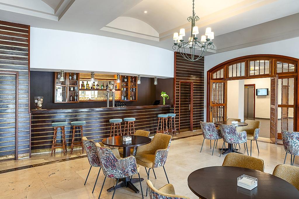 Parador Cañadas del Teide, Stilvolle und modern gestaltete Hotelbar mit einer eleganten Theke, gemütlichen Barhockern, stimmungsvoller Beleuchtung und einer großen Auswahl an Getränken im Hintergrund.