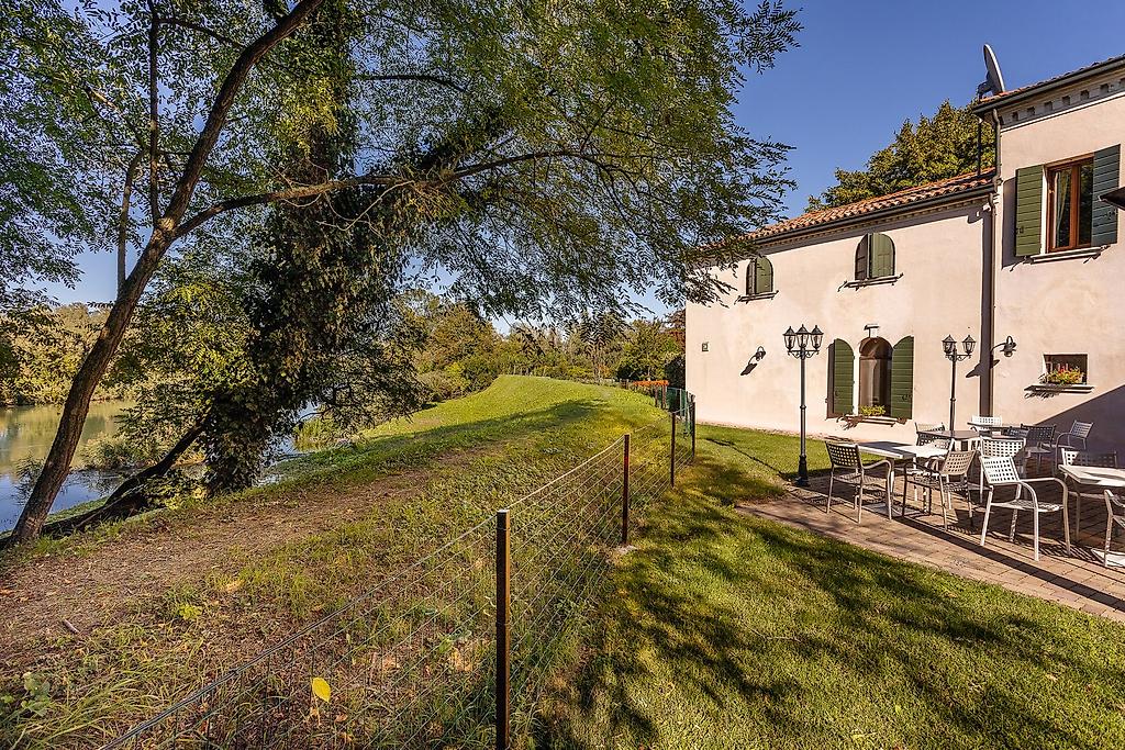 Borgo ca’ dei Sospiri, Ruhiges Flussufer mit Vegetation und Spazierweg