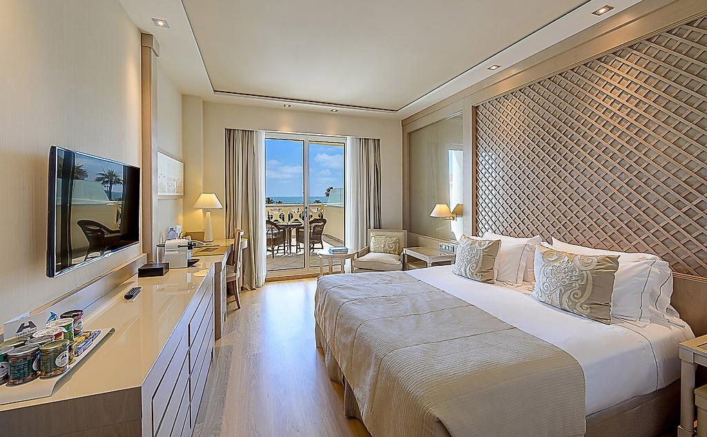 Hotel Las Arenas, Helles Deluxe-Zimmer mit Doppelbett, integrierter Sitzecke und moderner Kunst an der Wand.