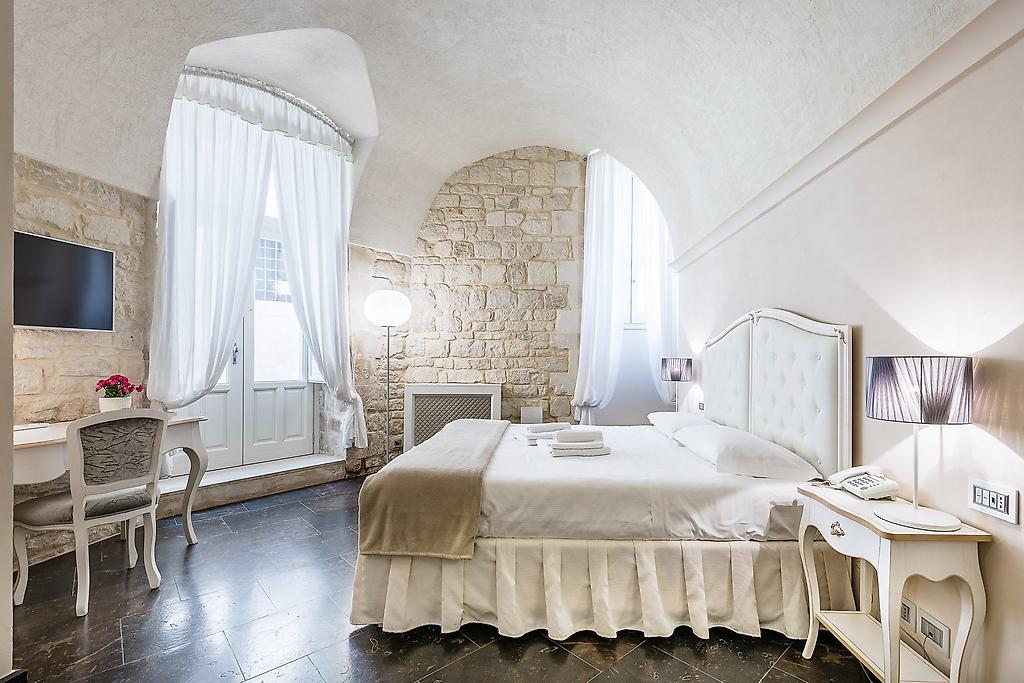 Scicli Albergo Diffuso, Geräumiges Deluxe‑Zimmer mit Doppelbett, Sitzbereich und warmen Akzenten.