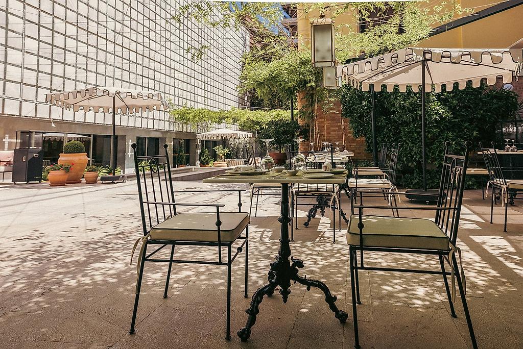 Hospes Palacio de los Patos, Ein idyllischer Hotelgarten mit schattenspendenden Bäumen, Sträuchern und einladenden Sitzgelegenheiten im Freien.