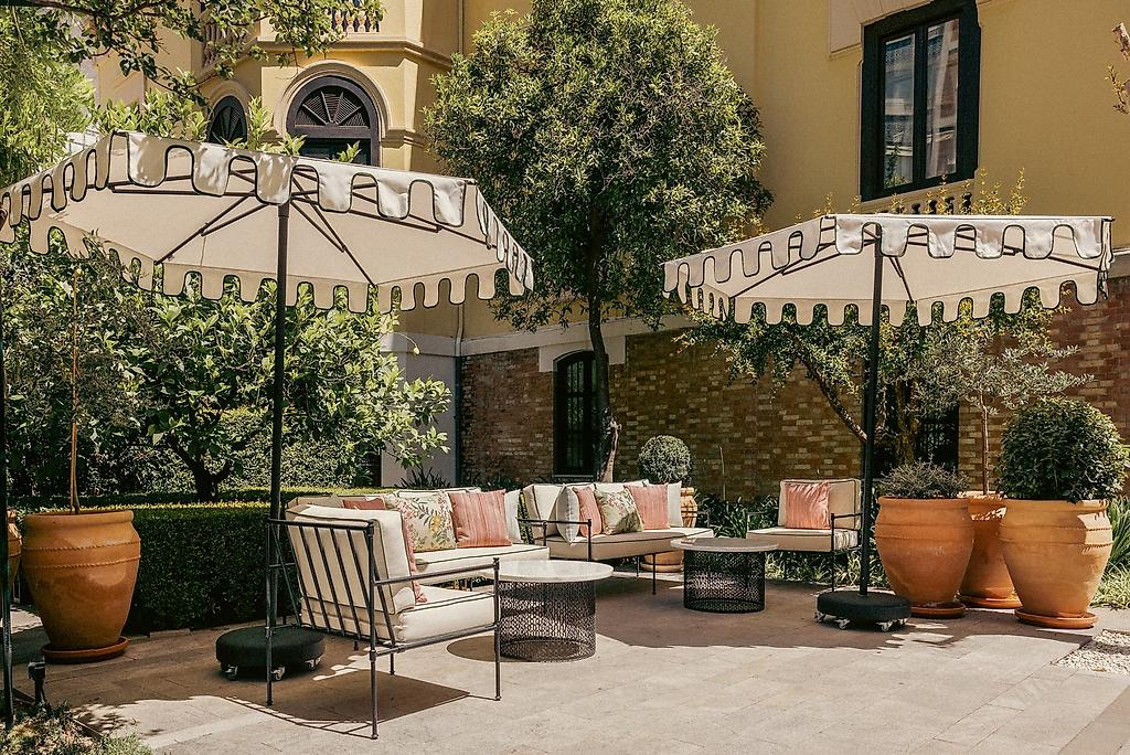Hospes Palacio de los Patos, Ein von Pflanzen und Bäumen gesäumter, gepflasterter Weg, der durch die gepflegte Gartenanlage des Hotels führt.