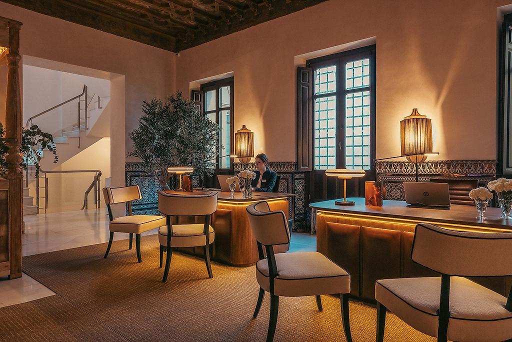Hospes Palacio de los Patos, Einladender, hell gestalteter Rezeptionsbereich des Hotels mit einem modernen Empfangstresen und stilvollem Design.
