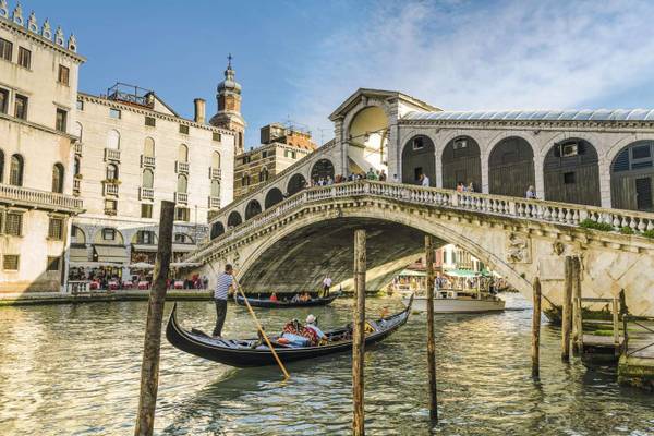 Gondeln auf dem Wasser, die unter einer rundgebogenen Brücke hindurchfahren Venedig