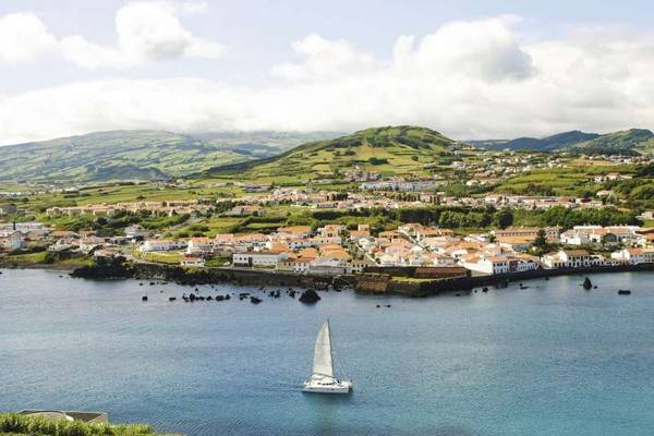 Blick vom Meer auf Horta auf Faial mit wolkenverhangenen Bergen im Hintergrund