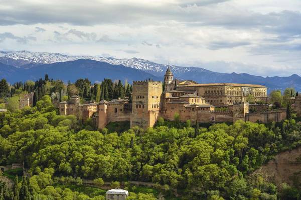 Alhambra umgeben von Bäumen und Berge im Hintergrund in Granada