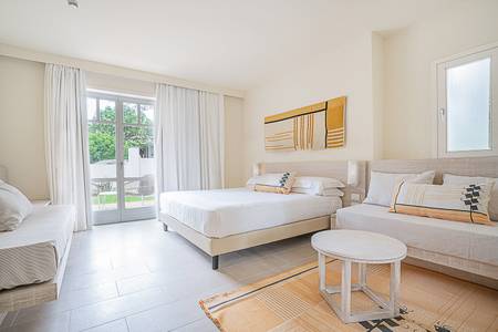 Hotel La Coluccia, Heller Wohn- und Schlafbereich in einer Garden Junior Suite.