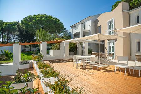 Hotel La Coluccia, Elegante Terrasse mit Tischen und Sonnenschirmen für den Aufenthalt im Freien.