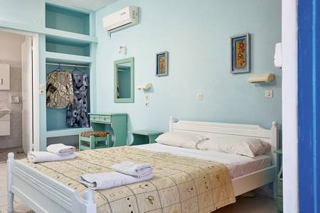 Glaros, Zimmer/Wohnbeispiel Glaros, Stilvoll eingerichtetes Hotelzimmer mit Doppelbett, türkisfarbenen Akzenten und Blick ins Grüne.