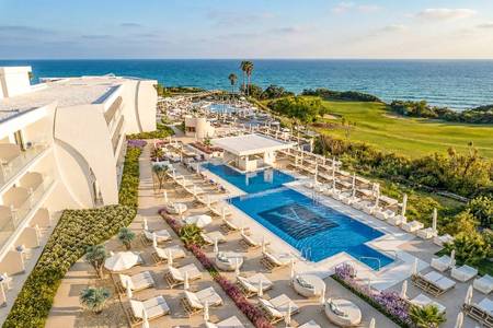 Amàre Beach Hotel Sancti Petri, Pool/Poolbereich Amàre Beach Hotel Sancti Petri, Großzügige Außenpool-Anlage unter blauem Himmel, umgeben von einer gepflegten Sonnenterrasse mit zahlreichen Liegestühlen und Palmen.