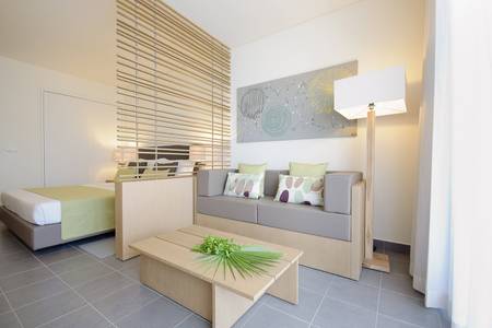 Oásis Salinas Sea, Blick in ein modernes Hotelzimmer mit Sitzecke, TV und dekorativen Wandelementen.
