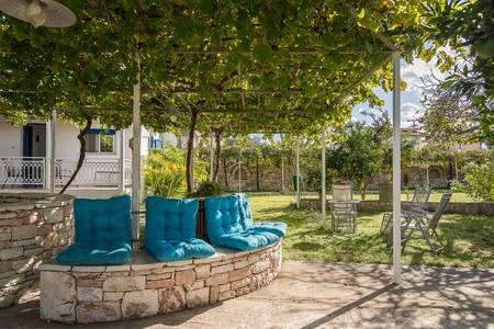 Villa Ganios, Gepflegte Gartenanlage mit mediterranen Pflanzen, Palmen und gepflasterten Gehwegen.